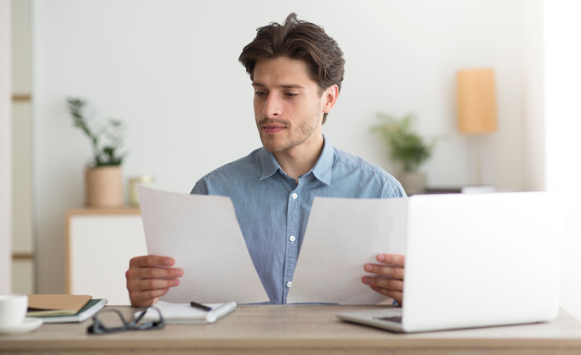 Homem lendo documentos em uma mesa em um ambiente de escritório moderno e brilhante